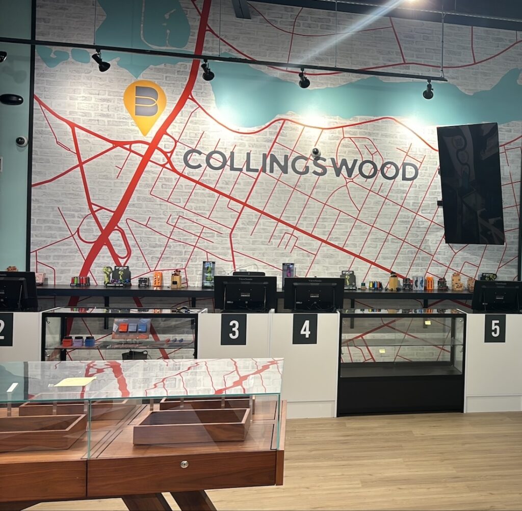 Interior of a modern retail store with numbered checkout counters and a large wall map of Collingswood in the background